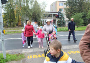 Przedszkolaki podczas przechodzenia przez ulicę pod opieką funkcjonariusza Policji i wychowawców